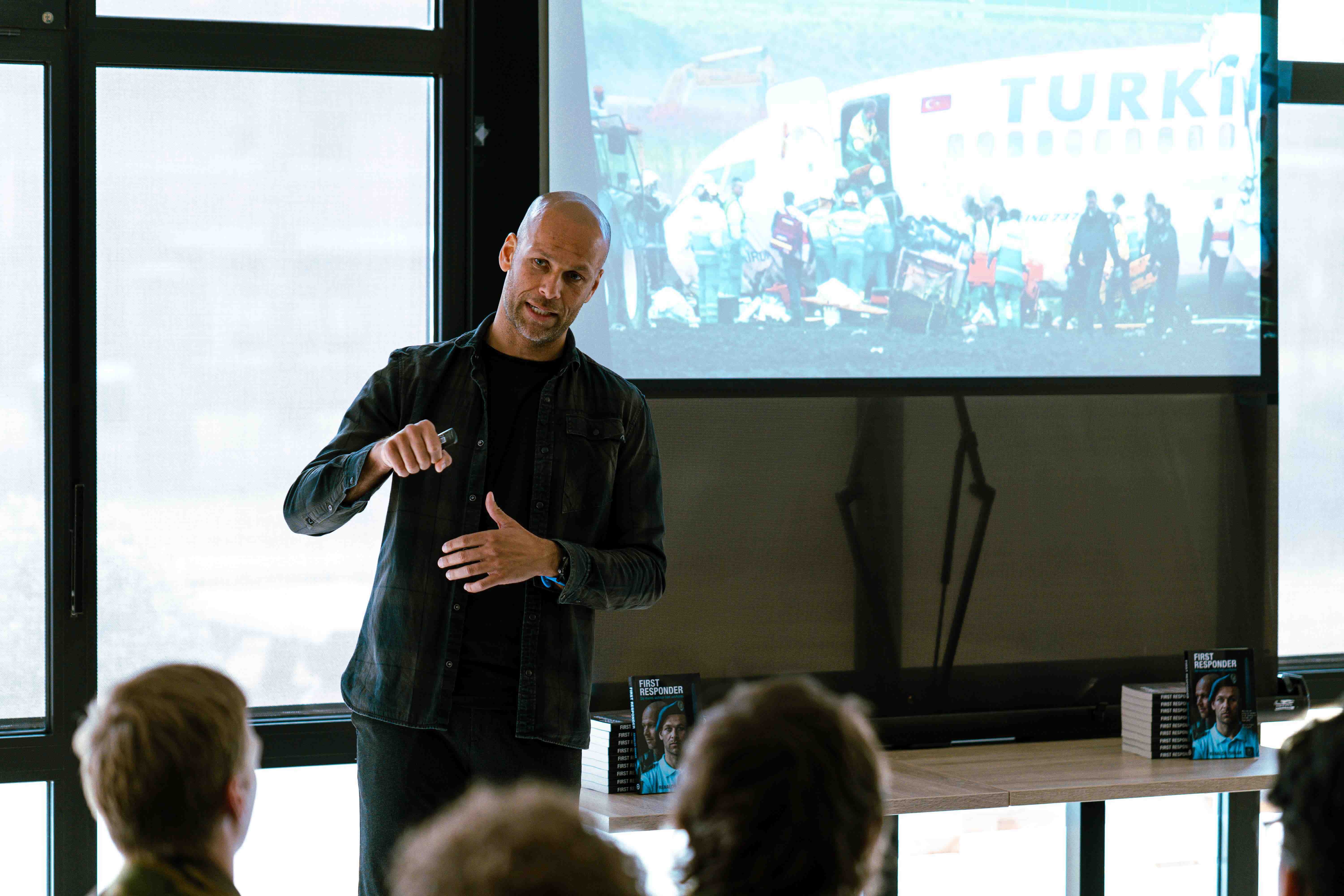 Renaldo Ishaal voor een scherm en publiek een lezing geven