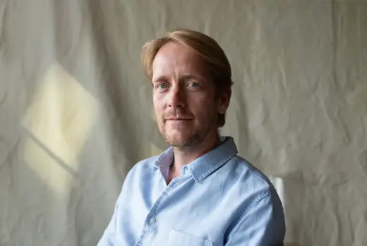 Sander Heijne in blouwe blouse met gekreukelde achtegrond