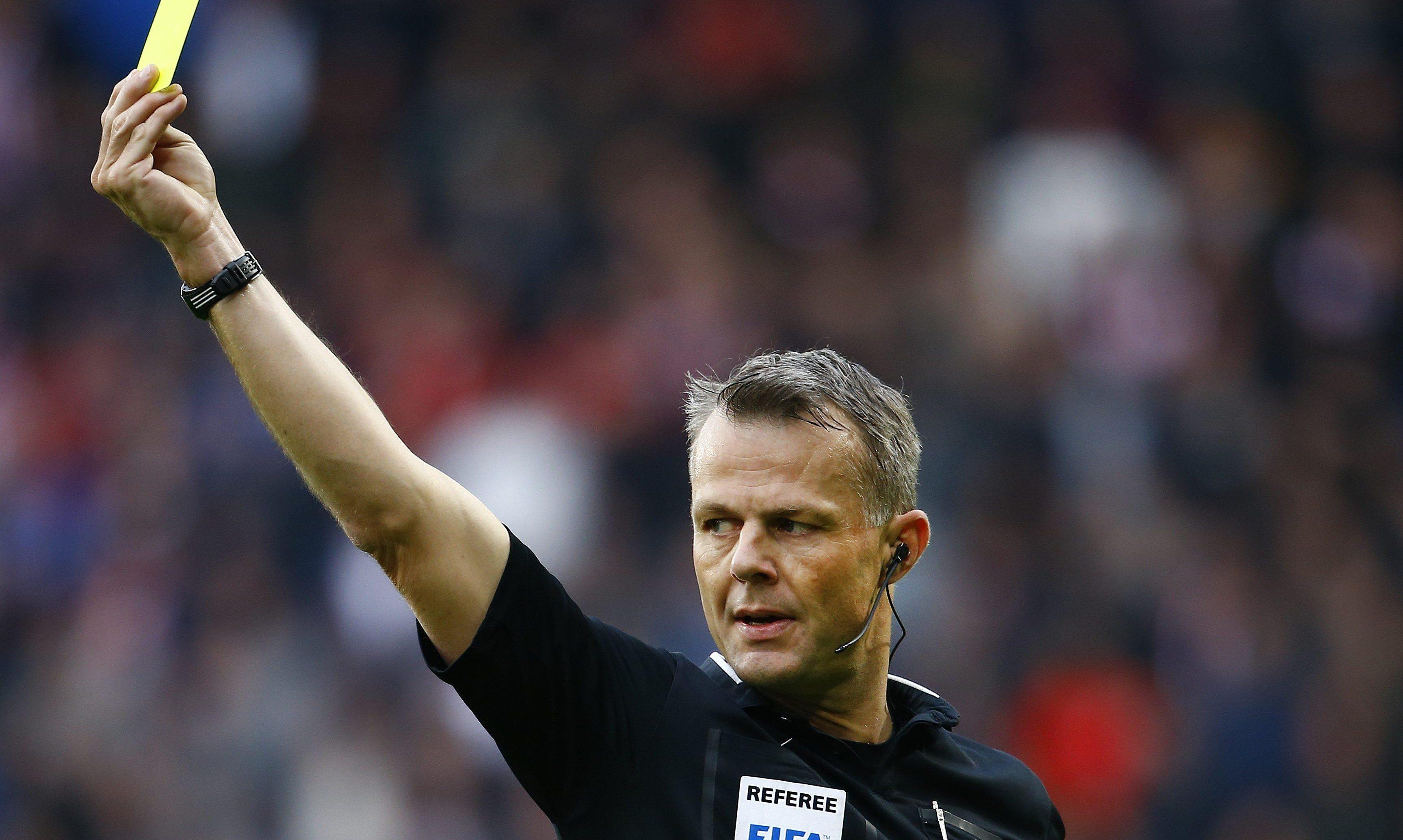 Björn Kuipers in voetbalstadion met gele kaart in hand