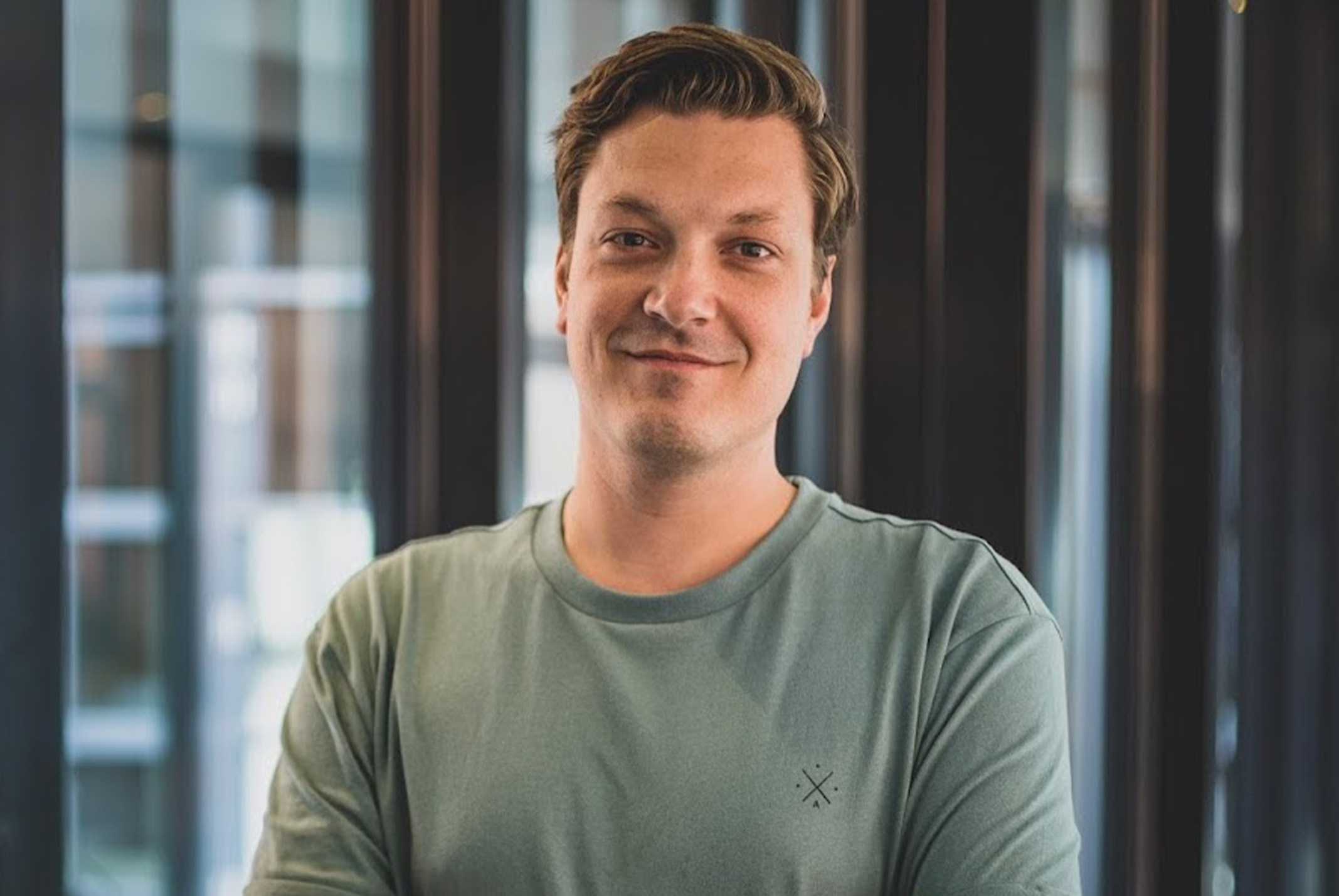 Jelle Maasbach glimlachend in groene shirt bij ramen