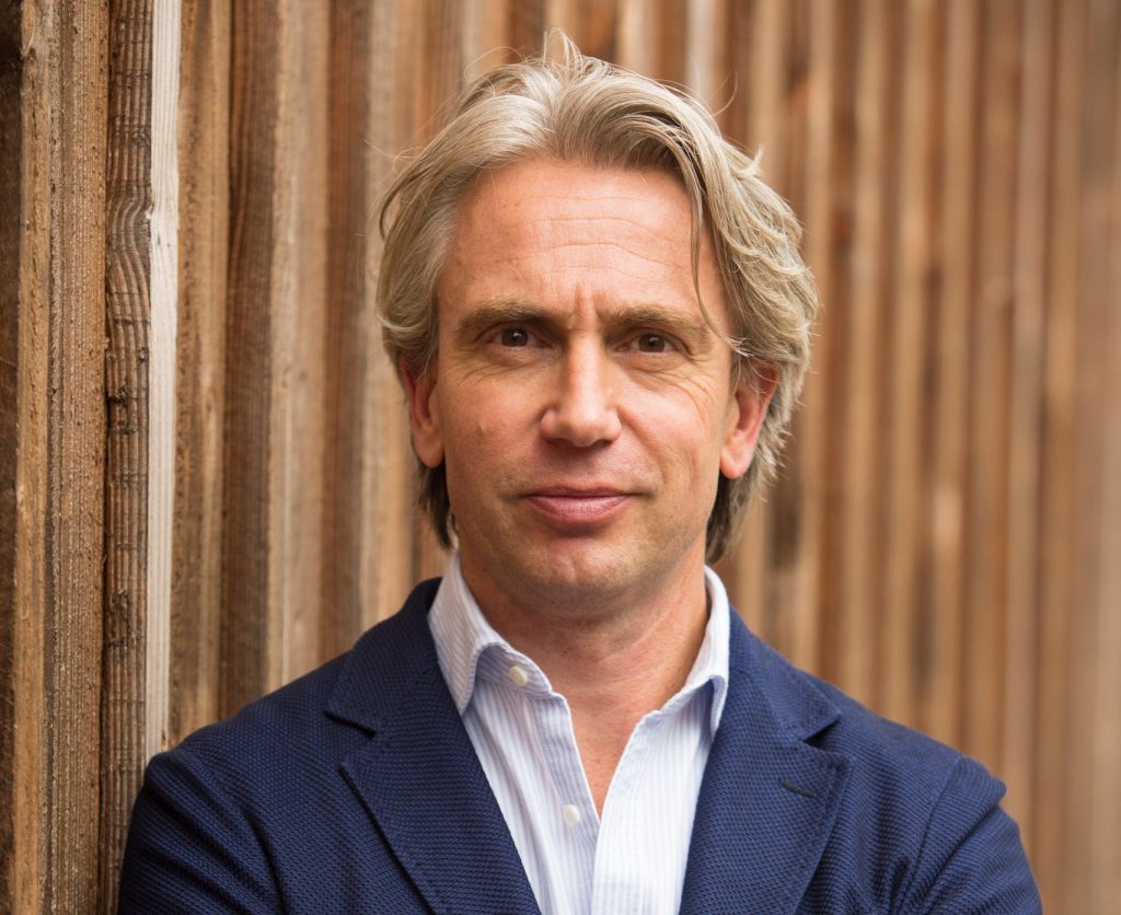 Menno Lanting in pak bij houten muur