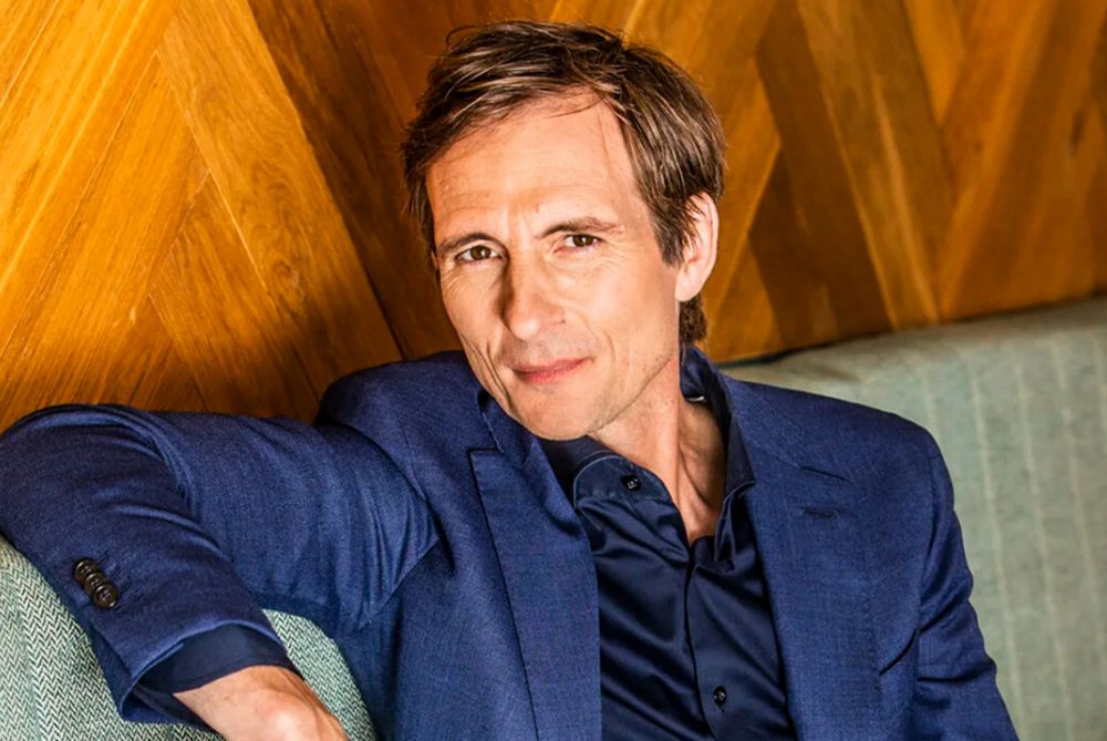 Michiel Vos op de bank in blauw pak