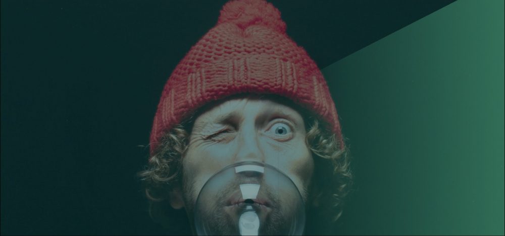 Spreker met muts op blaast een bel met kauwgom