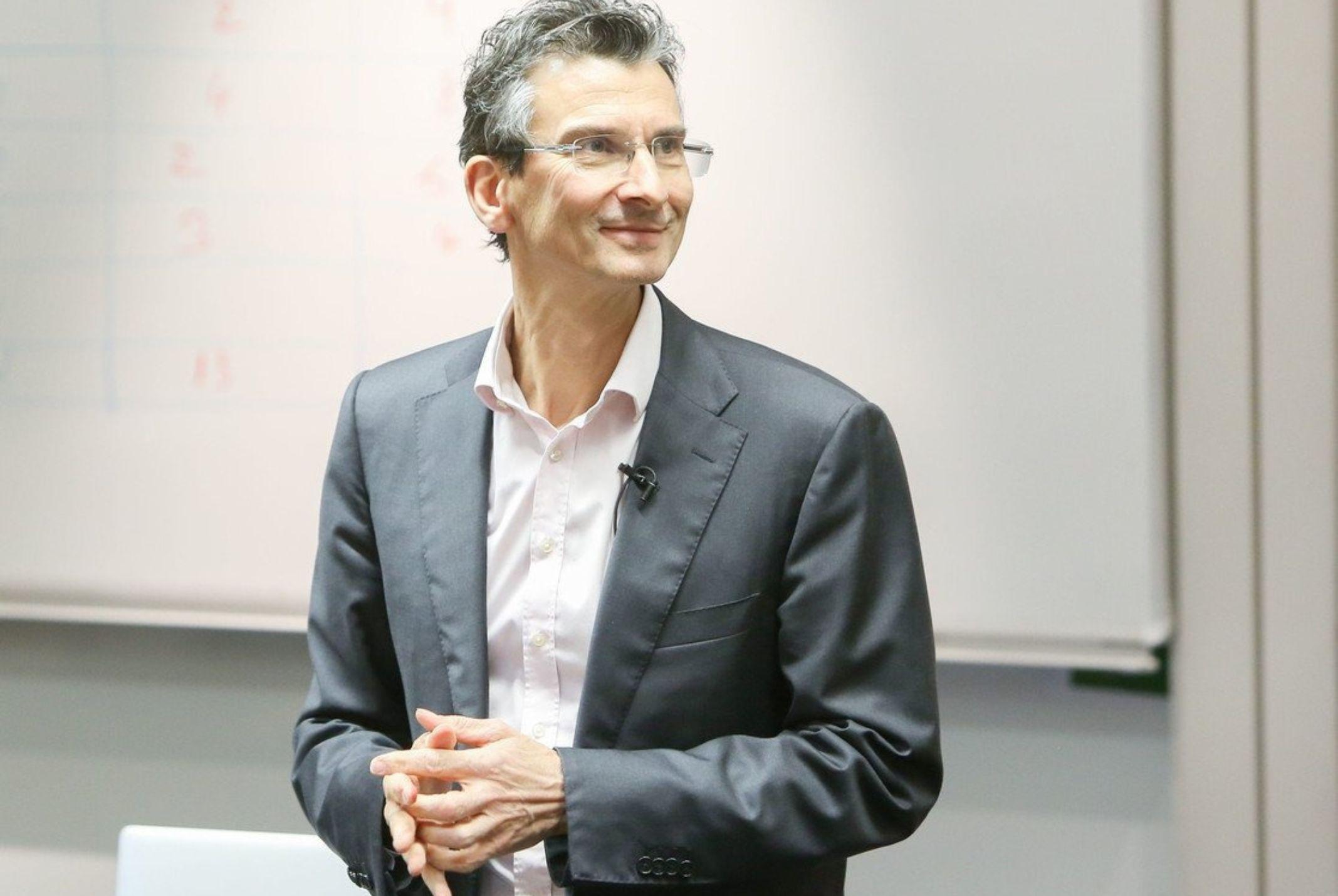 David Lewis in collegezaal en grijze colbert